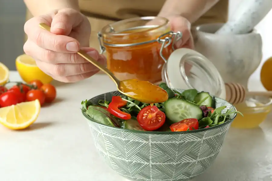 Un frasco de miel junto a frutas frescas y pan